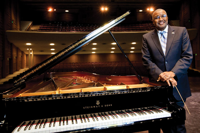 Marvin Curtis stands next to a piano
