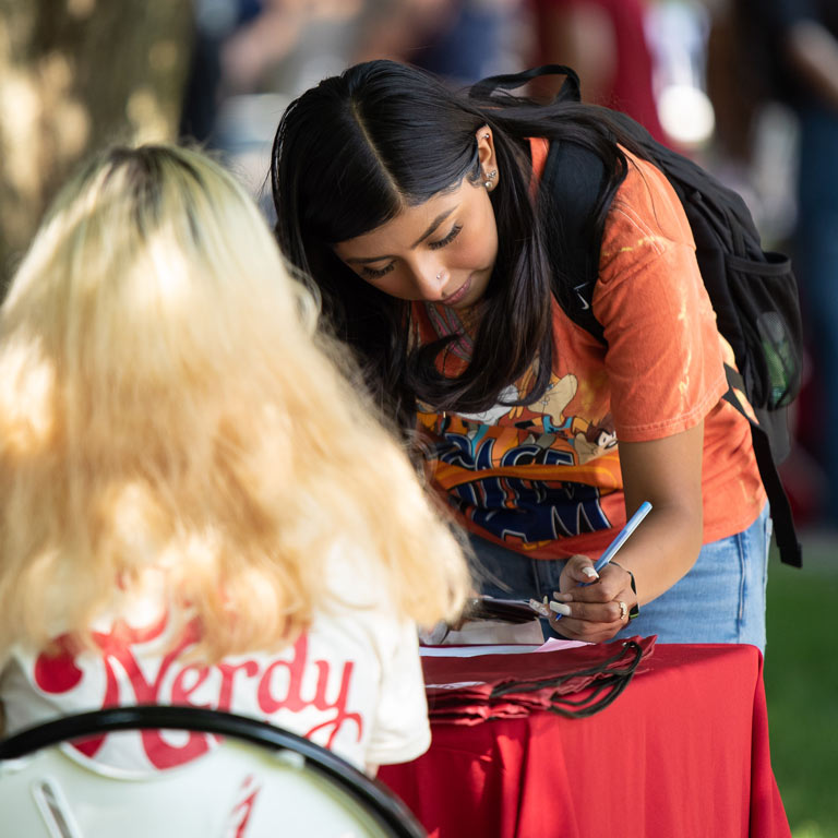 female student signing up at welcome back table