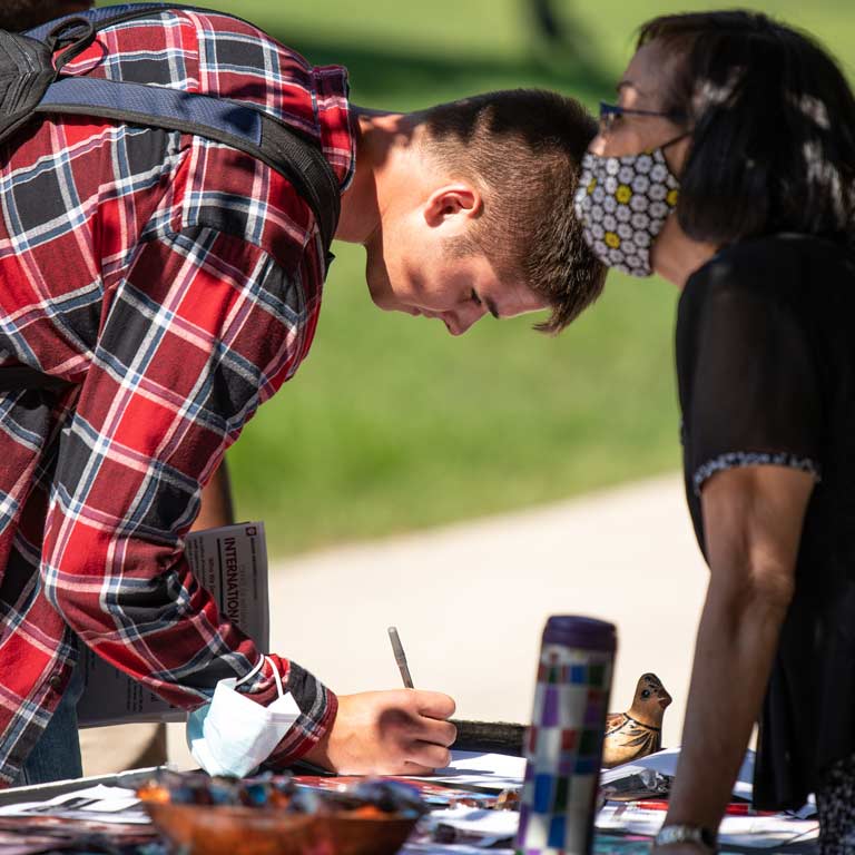 male student signing up at welcome back fair